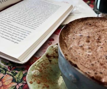 capuccino e um livro na mesa do chá e bolachas- cafetaria para visitar em Aveiro